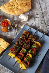 drei spieße Schisch Kebab mit Lammfleisch Paprika und Zwiebeln auf grauem teller und Holztisch...