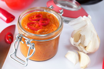 Würziges Ajvar in Einmachglas mit Messer Chili Knoblauch Paprika