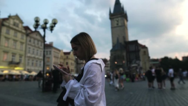 The girl works on the phone in the center of Prague
