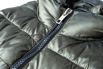 Close-up zipper closure on a light warm olive-colored jacket. Warm clothes, accessories for...
