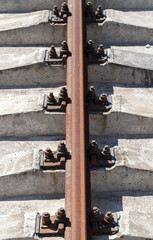 Rusty rail on concrete sleepers. Vertical photo