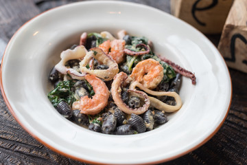 Black Conchiglie Pasta Shells with Seafood, Spinach and Cream Sauce. Modern Cafe Lunch.