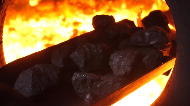 Throwing coals with shovel into the furnace