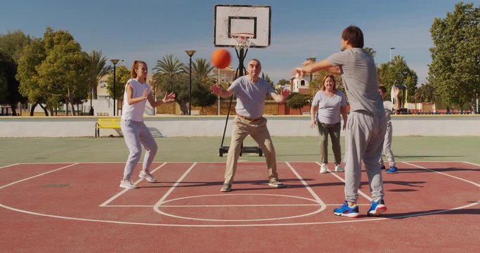 Multigeneration family playing basketball on outdoor court.