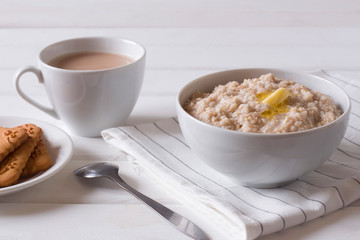 oatmeal with butter, tea and cookies on the table