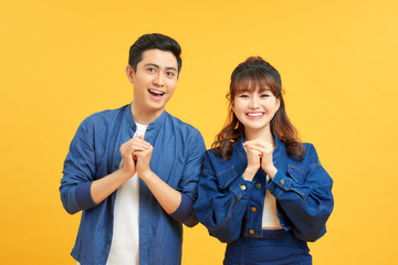 Young couple posing congrat gesture in a yellow background