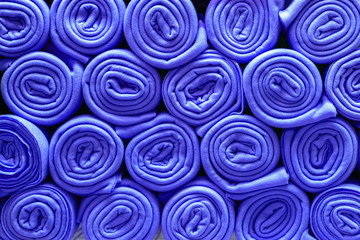 Pile of folded blue blankets. Rolls of blue plaids lie on a shelf, texture effect.