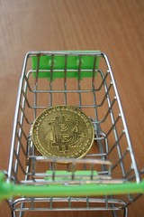 Bitcoin inside mini shopping trolley as in business creative concept. Cryptocurrency background.