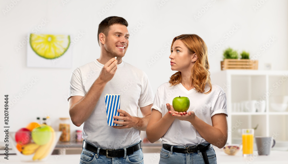 Sticker food, eating and diet concept - portrait of happy couple in white t-shirts with popcorn and green ap