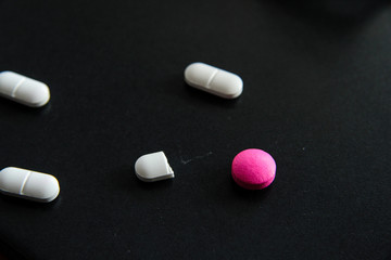 Various medical pills on black background health concept  