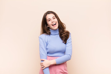young pretty woman laughing shyly and cheerfully, with a friendly and positive but insecure...