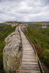 Fototapeta na wymiar Wooden bridge on the stone wall of an ancient defensive structure-Ovech fortress in Bulgaria. Old planks of a wooden road on top of a cliff