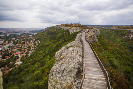 Wooden bridge on the stone wall of an ancient defensive structure-Ovech fortress in Bulgaria. Old planks of a wooden road on top of a cliff