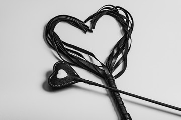 Card for Valentine's Day. BDSM riding crop and leather whip in the form of a heart. Sex toys for love games. - obrazy, fototapety, plakaty