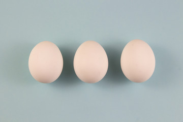 Three white chicken eggs on a blue background. place for text, easter holiday concept