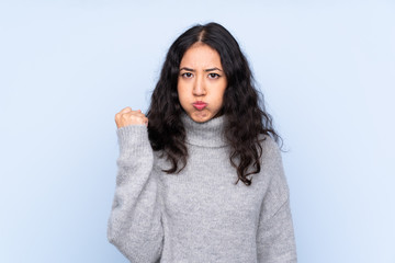 Fototapeta premium Spanish Chinese woman over isolated blue background with angry gesture