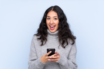 Fototapeta premium Spanish Chinese woman over isolated blue background surprised and sending a message