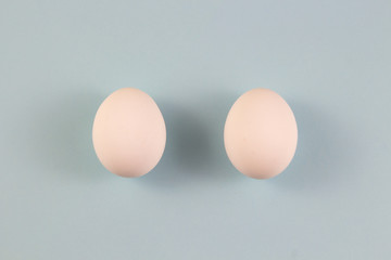 two white chicken eggs on a blue background. place for text, easter holiday concept