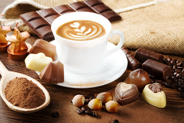 cup of delicious latte with chocolate and roasted coffee beans covered in burlap