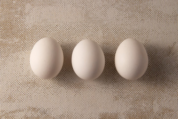 Three white chicken eggs on a blue background. place for text, easter holiday concept