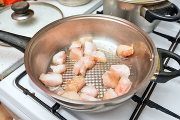 Pork fat is fried in a pan on a gas stove in the kitchen at home.