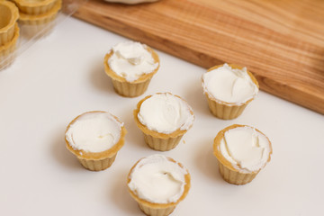 Tartlets with custard or cottage cheese. Empty tartlets or pie on a white table. Food lay flat. The view from the top. The concept of preparing food for the holiday table.