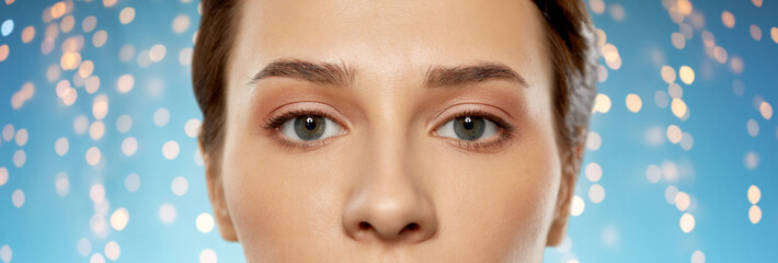 beauty, makeup and vision concept - close up of beautiful young woman face and eyes over holidays...