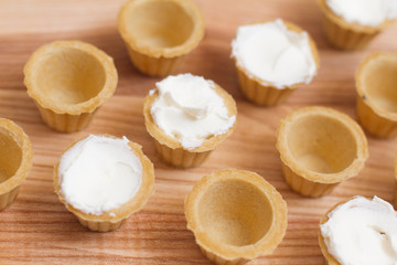 Obraz na płótnie Canvas Tartlets with custard or cottage cheese. Empty tartlets or pie on a white table. Food lay flat. The view from the top. The concept of preparing food for the holiday table.