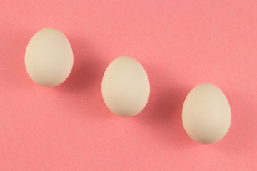 Three white chicken eggs on a pink background. place for text, easter holiday concept