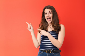 young pretty woman feeling joyful and surprised, smiling with a shocked expression and pointing to...