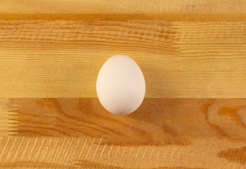 one white chicken egg on a wooden background. place for text, easter holiday concept