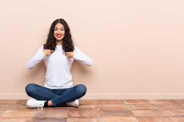 Young woman sitting on the floor with surprise facial expression