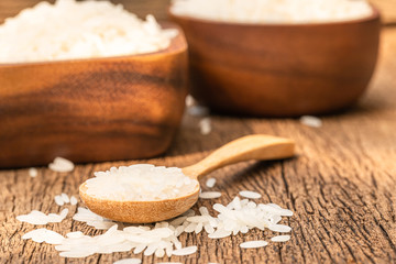 Close up a lot of long grain rice on a wooden spoon on wooden background.