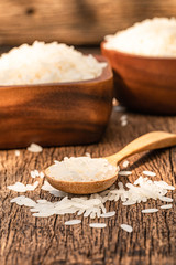 Close up a lot of long grain rice on a wooden spoon on wooden background.