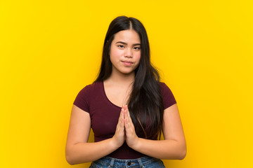 Obraz premium Young teenager Asian girl over isolated yellow background pleading