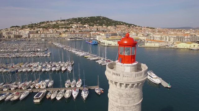Nice drone shot of Sete's harbor, south of France. Nice red lighthouse and sailboat with the Mont Saint Clair in background.