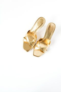 Gold female slippers shoes on white linen. Minimal flat lay fashion composition. Top view glamour accessory concept.