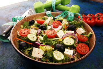 Authentic fresh salad in a stone cup with dumbbells excercise equipment, measuring tape on table. healthy lifestyles, good health Concept with fresh ingredients