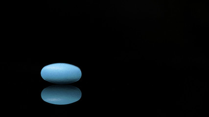 Fototapeta na wymiar oval medical tablet isolated on a black background with reflections. the concept of drugs.
