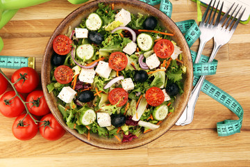 Authentic fresh salad in a stone cup with dumbbells excercise equipment, measuring tape on table. healthy lifestyles, good health Concept with fresh ingredients