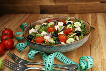 Authentic fresh salad in a stone cup with dumbbells excercise equipment, measuring tape on table. healthy lifestyles, good health Concept with fresh ingredients