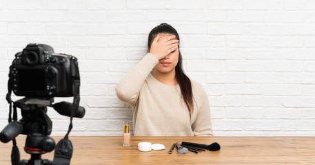 Young blogger Asian girl recording a video tutorial covering eyes by hands