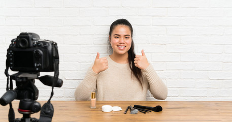 Young blogger Asian girl recording a video tutorial giving a thumbs up gesture