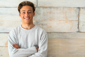 close up and portrait of teenager or boy smiling and looking at the camera with a wooden background...
