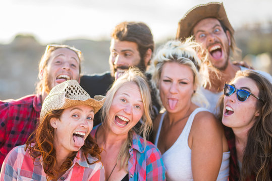 group of seven people together looking at the camera doing crazy and funny faces expressions - fun and happy caucasian people - cowboy and cowgirl in a ranch having fun enjoying