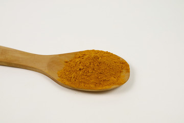 Turmeric powder in a wooden spoon isolated on a white background is used as a tonic for the body and food ingredients.