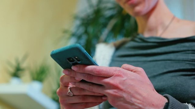 Housewife writes a message on a smartphone in the kitchen. 
