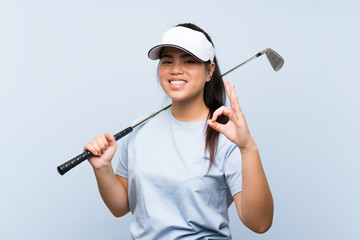 Young golfer Asian girl over isolated blue background showing ok sign with fingers