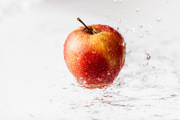 Jabłko w deszczu, polewane wodą. Widzoczne krople - obrazy, fototapety, plakaty