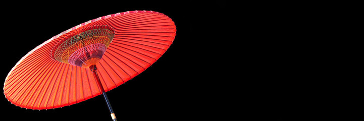 Red japanese umbrella on panoramic black background with copy space, Japan web banner